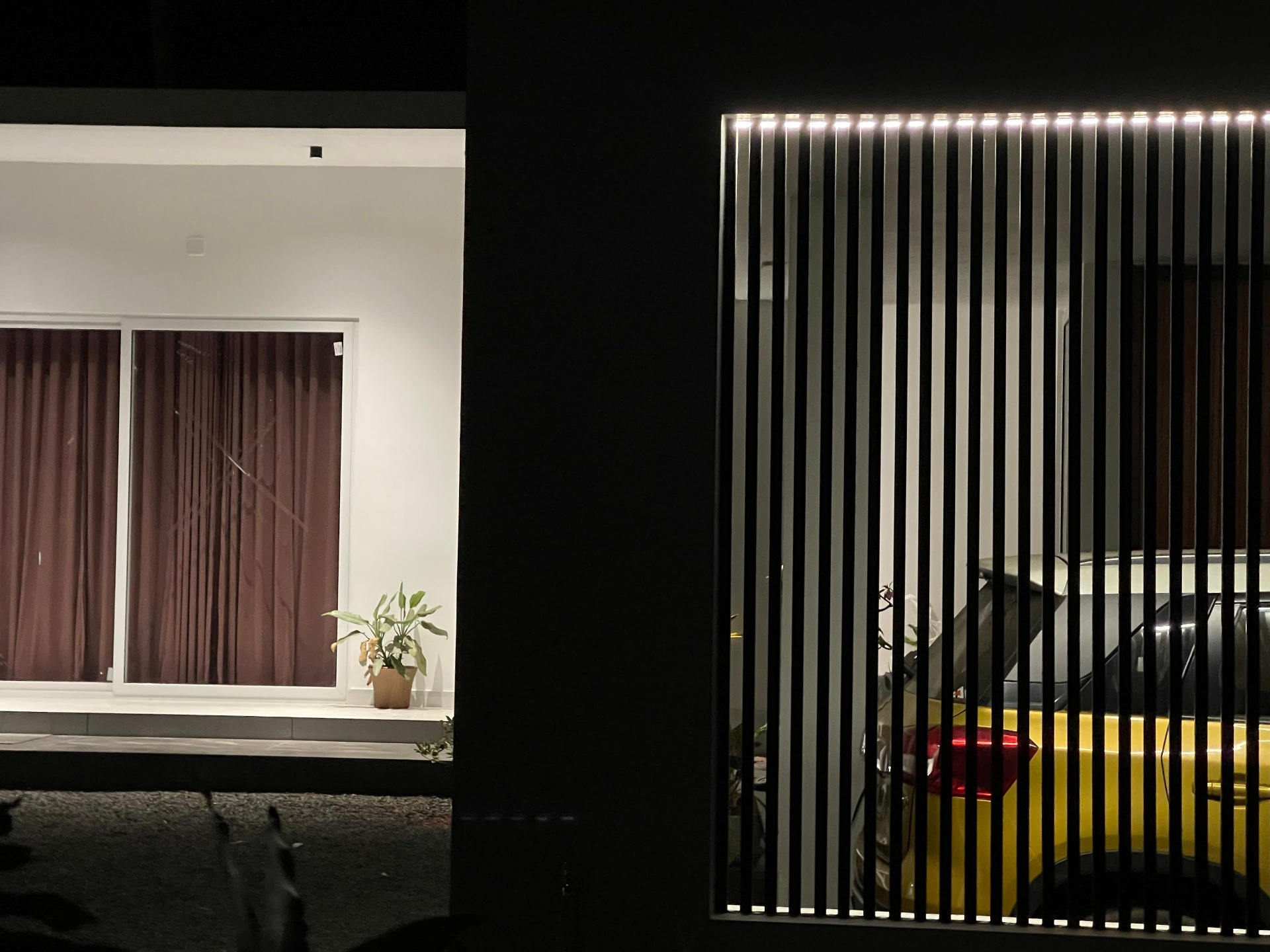 Exterior detail at night: white slat privacy screen with LED strip lighting and boundary carport by iptnirman