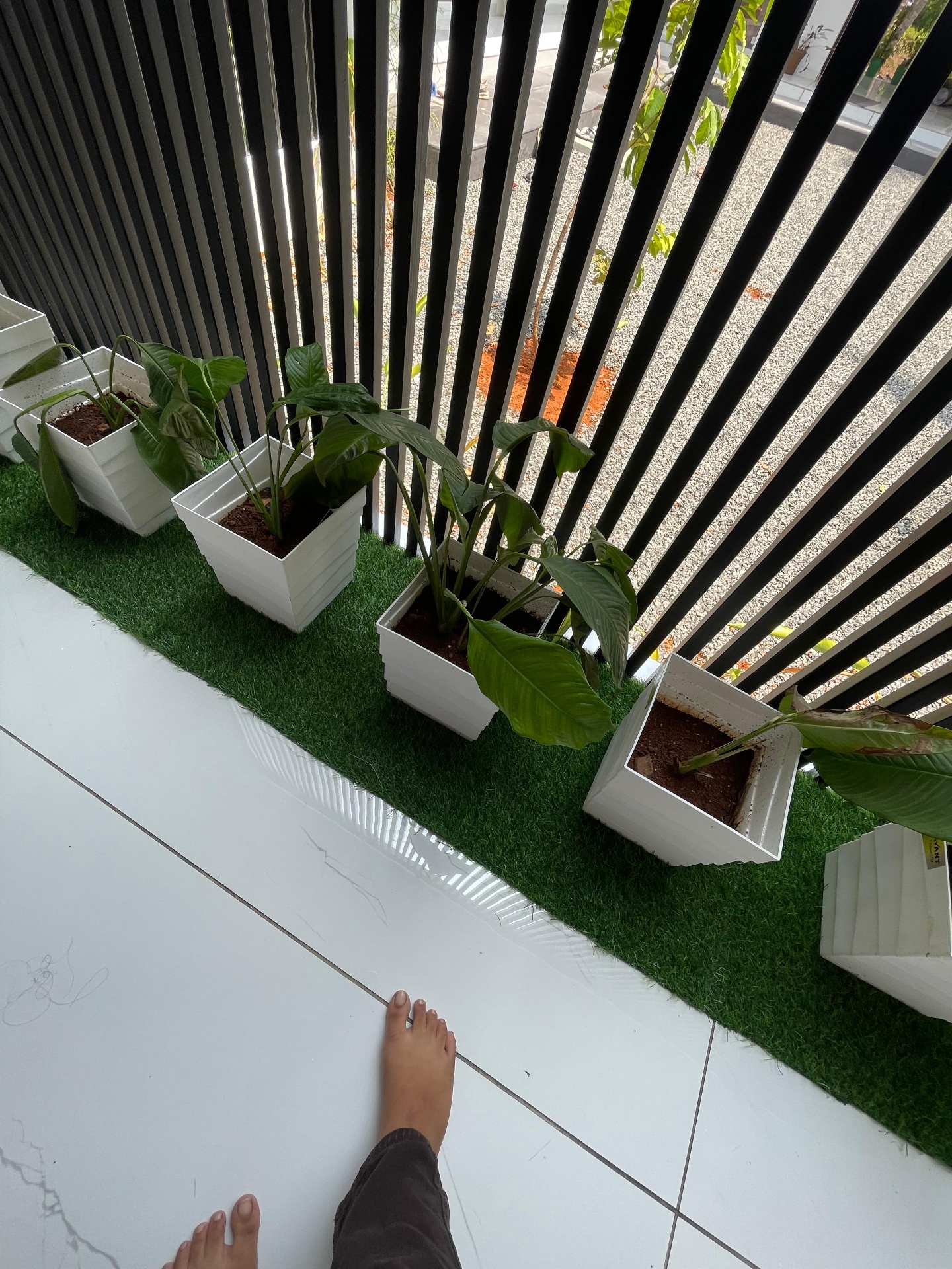 Balcony planter row on artificial turf against black vertical louver screen — iptnirman exterior detail